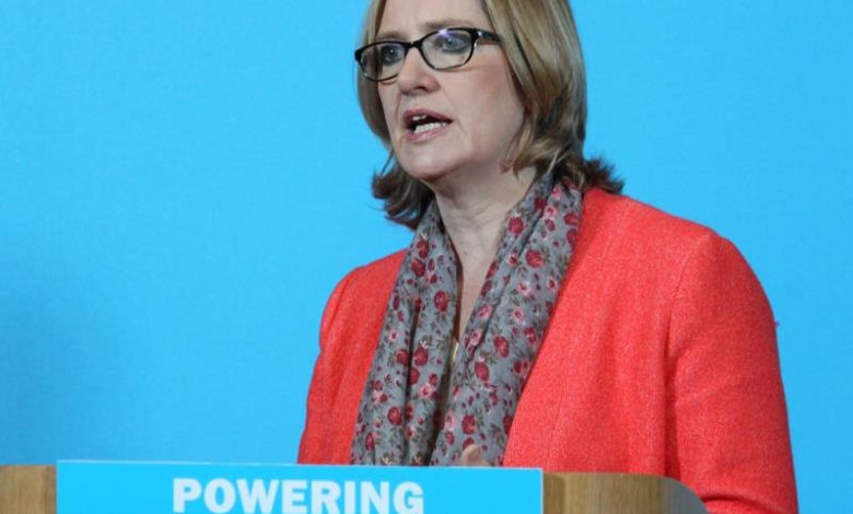 Amber Rudd giving a speech on a behind a desk with the inscription "Powering Britain's Future"